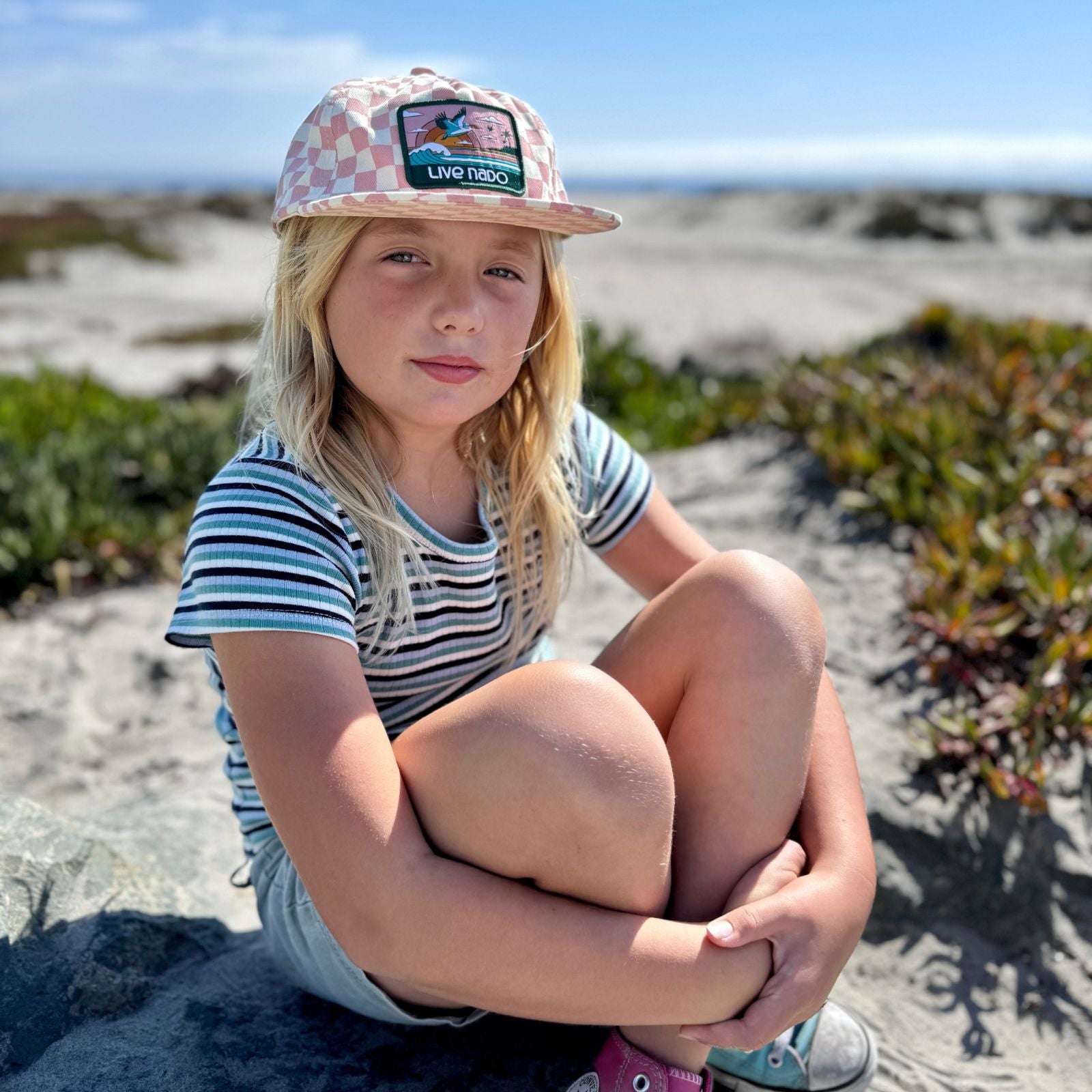 youth girl wearing a pink chekered flat brim surf cap