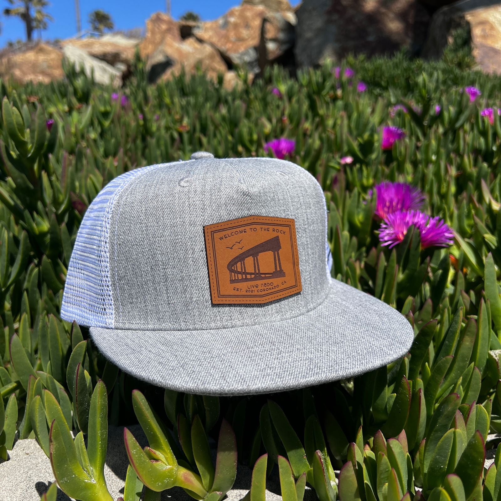 grey flat brim trucker with Welcome to the Rock leather patch