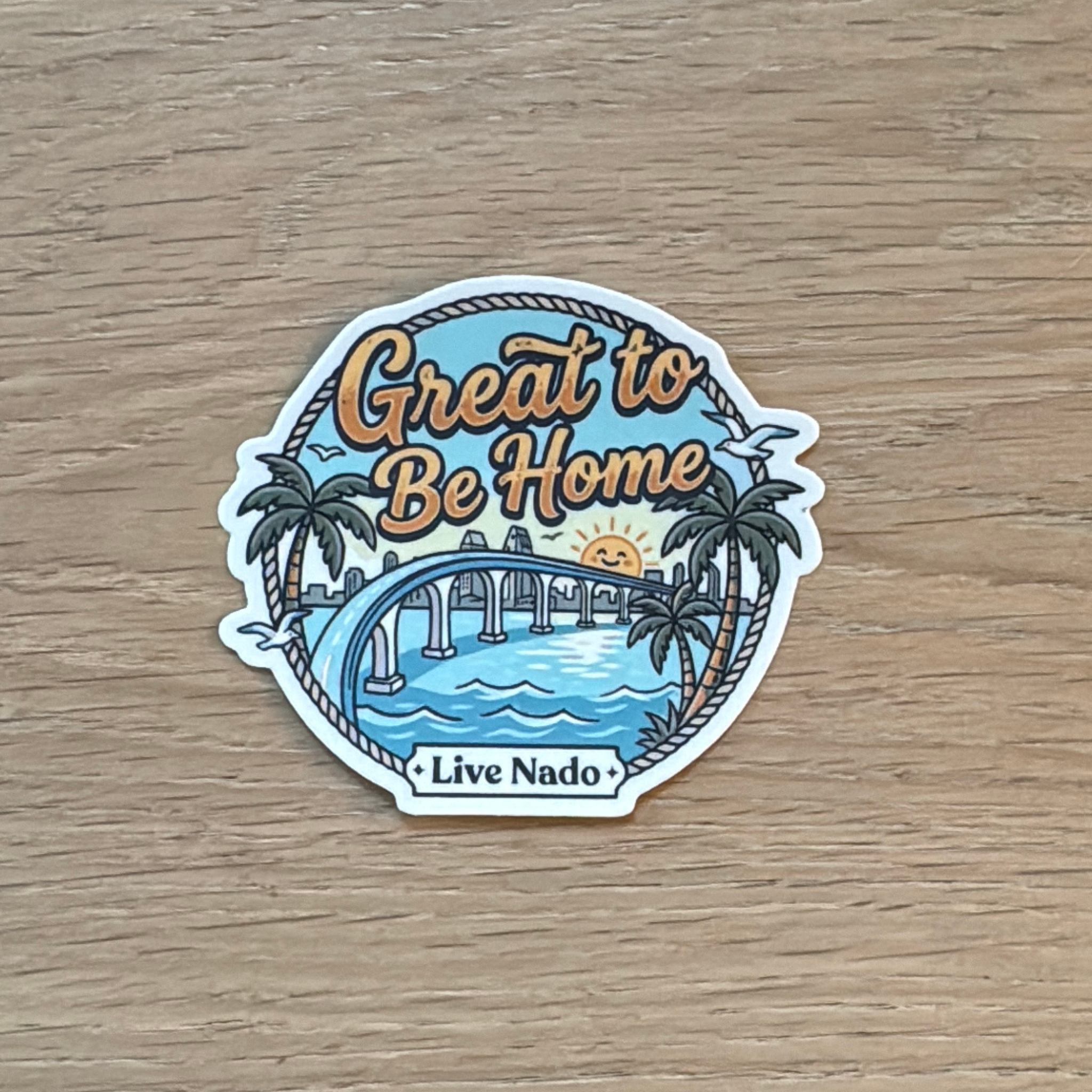Sticker with 'Great to Be Home' text and beach scene on a wooden surface