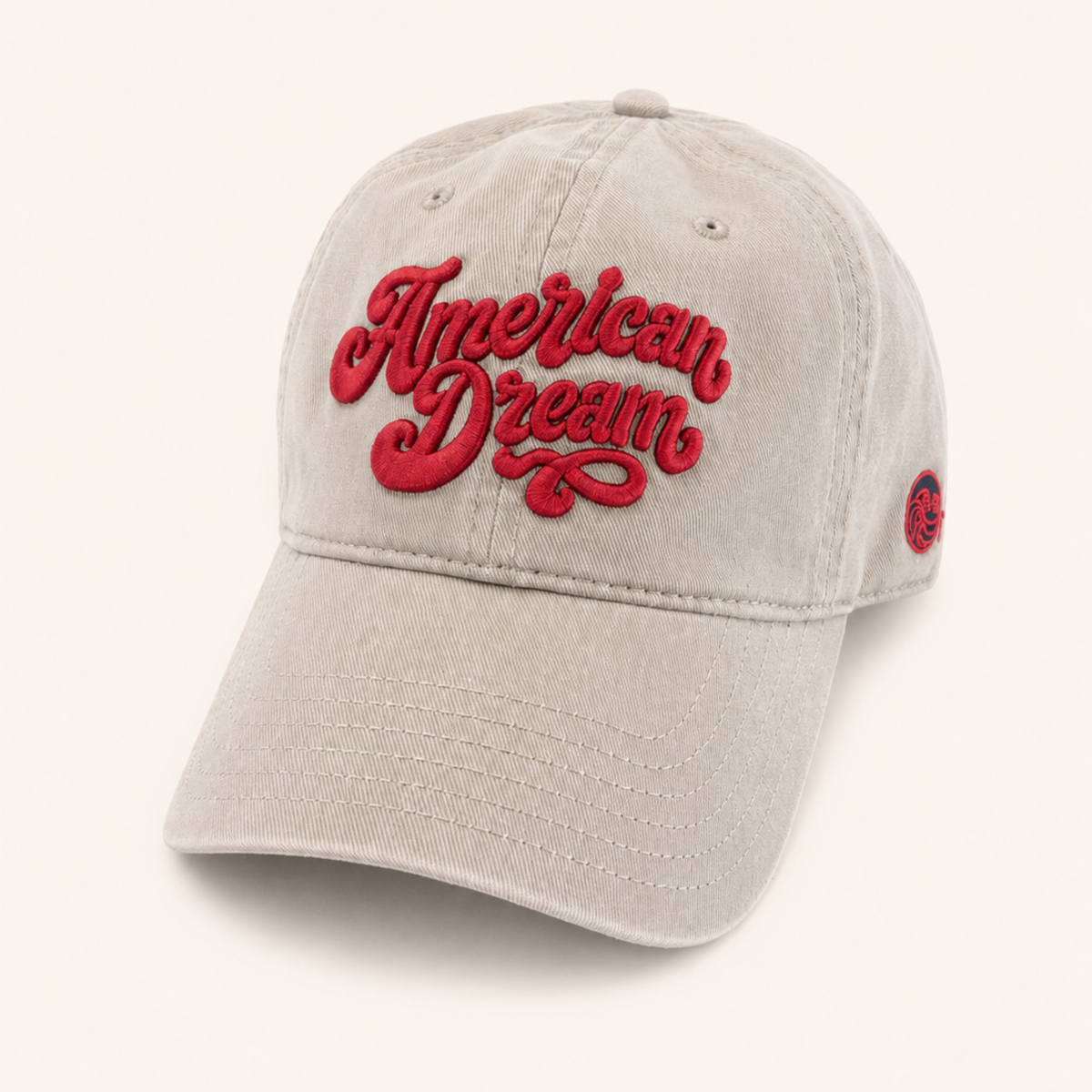 Tan baseball cap featuring "American Dream" embroidered in raised red script across the front.