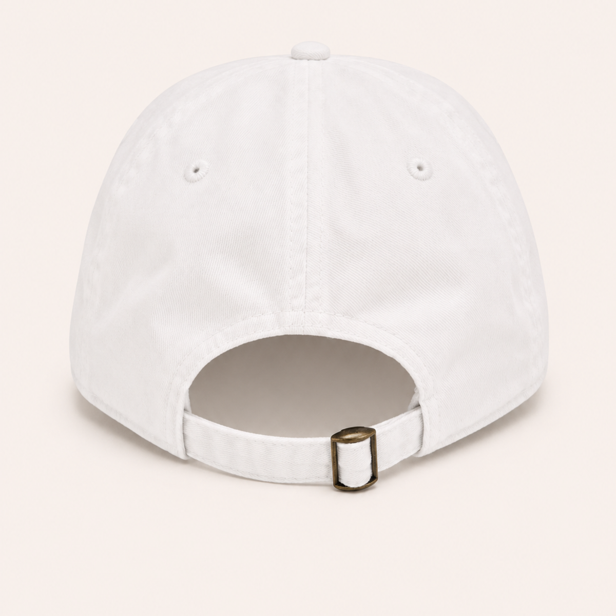 Back view of a plain white cotton baseball cap with an adjustable fabric strap and brass buckle.