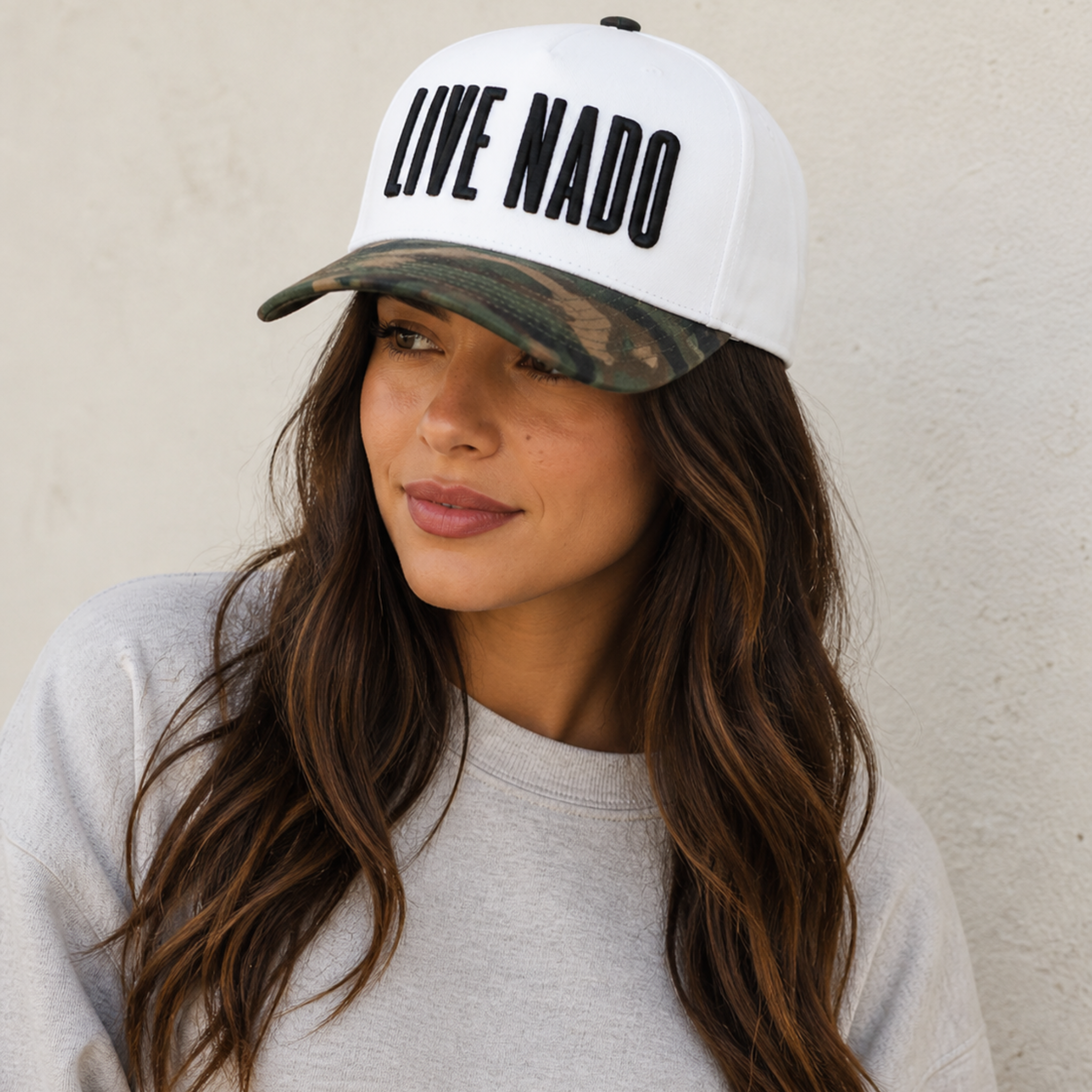 Woman wearing a cap with 'LIVE NADO' text against a neutral background