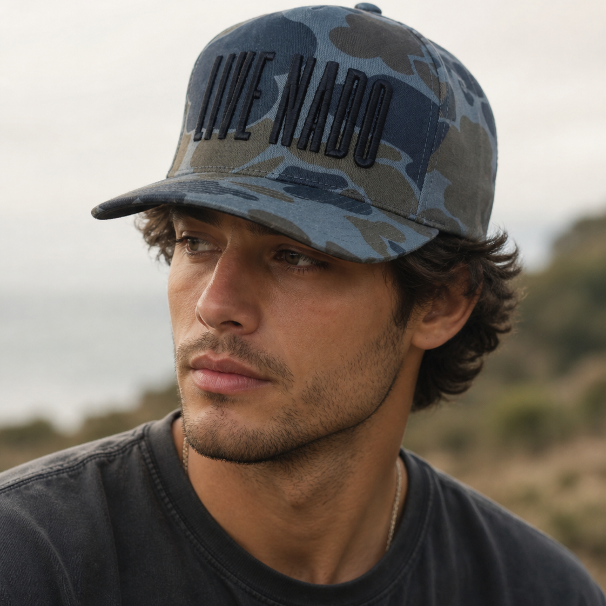 Man wearing a camouflage cap with 'LIVE NADO' text, outdoors.