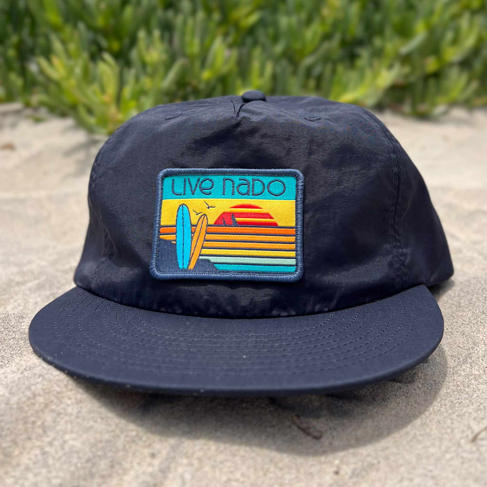 navy blue unstructured surf cap with flat brim. has retro colored embroidered surf board patch that looks like a beautiful Coronado, CA sunset.