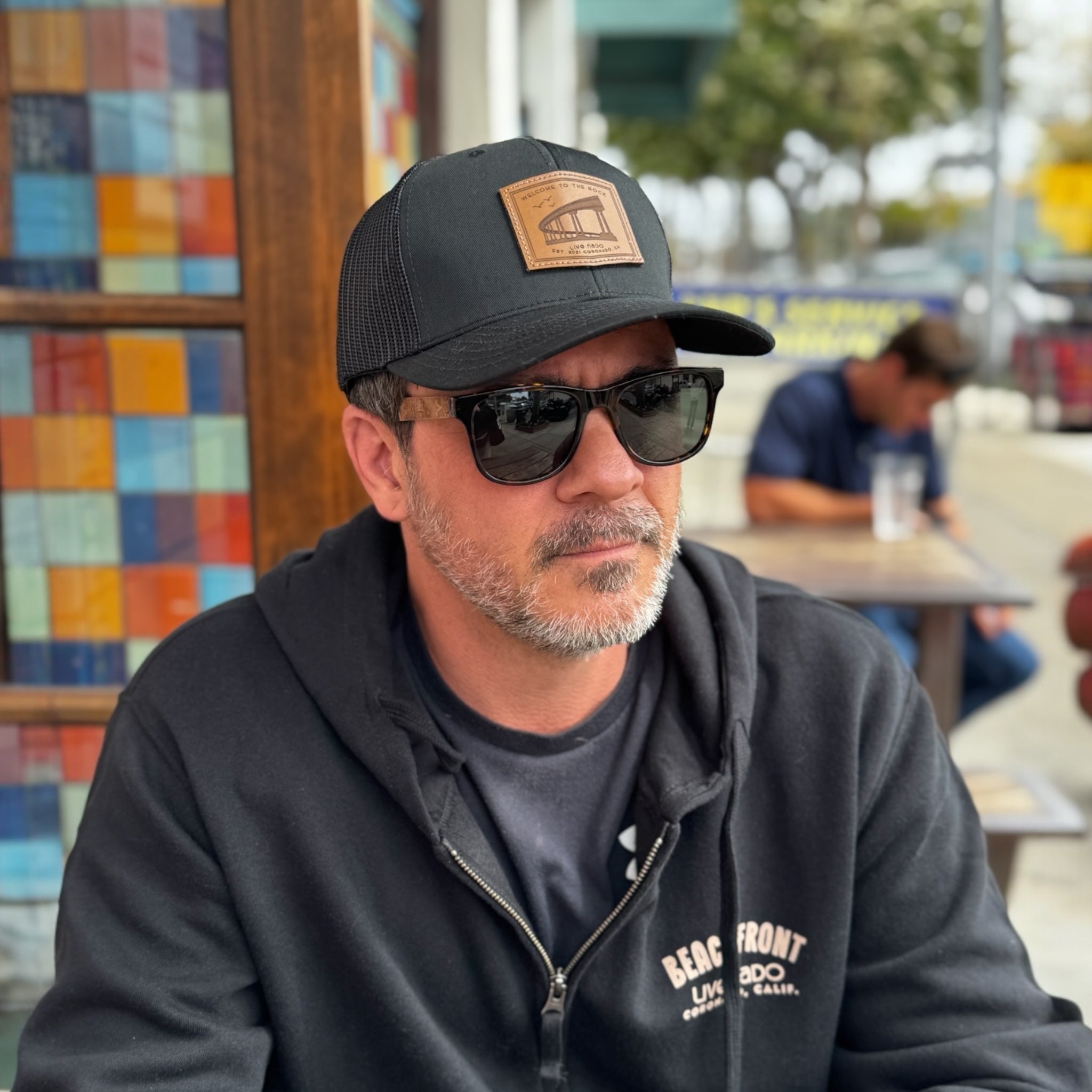 man wearing a black trucker cap with a brown leather patch