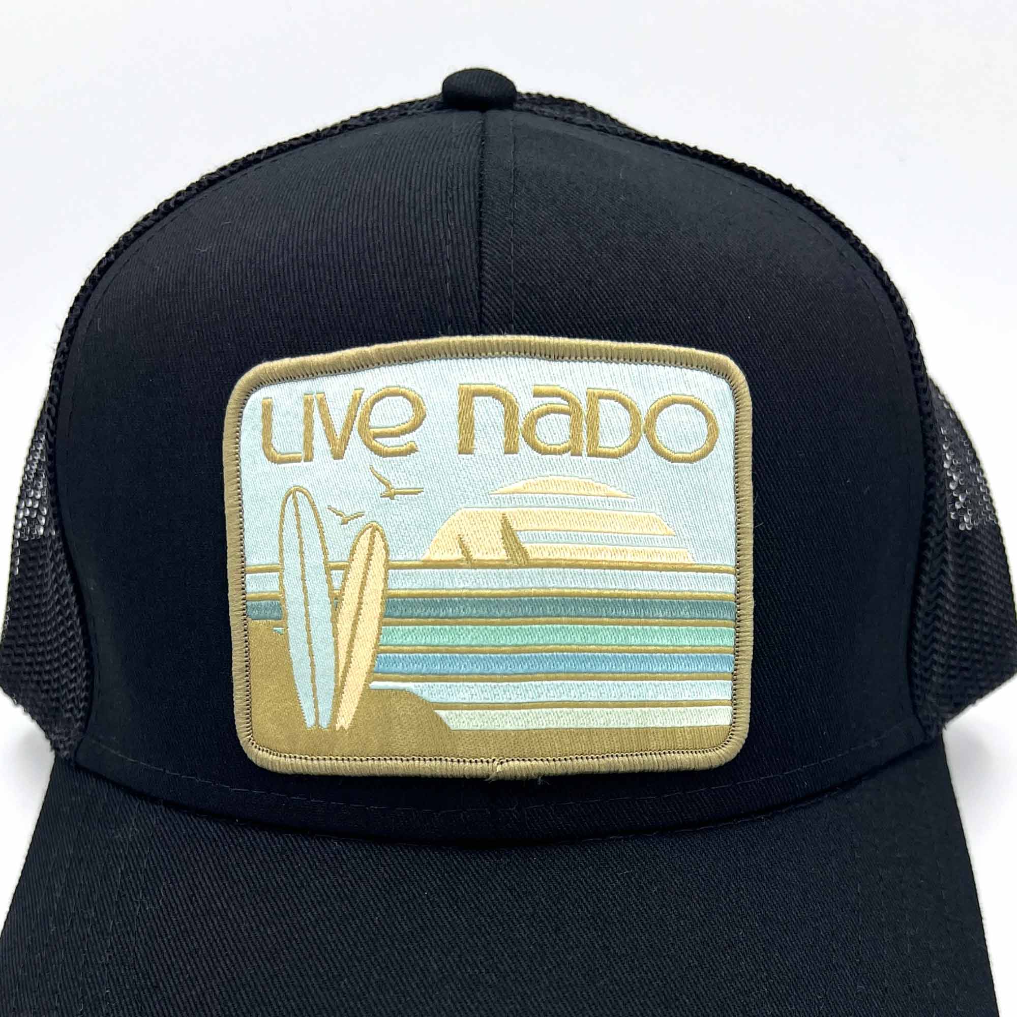 close up of neutral green embroidered surfboard patch on a black curved bill trucker