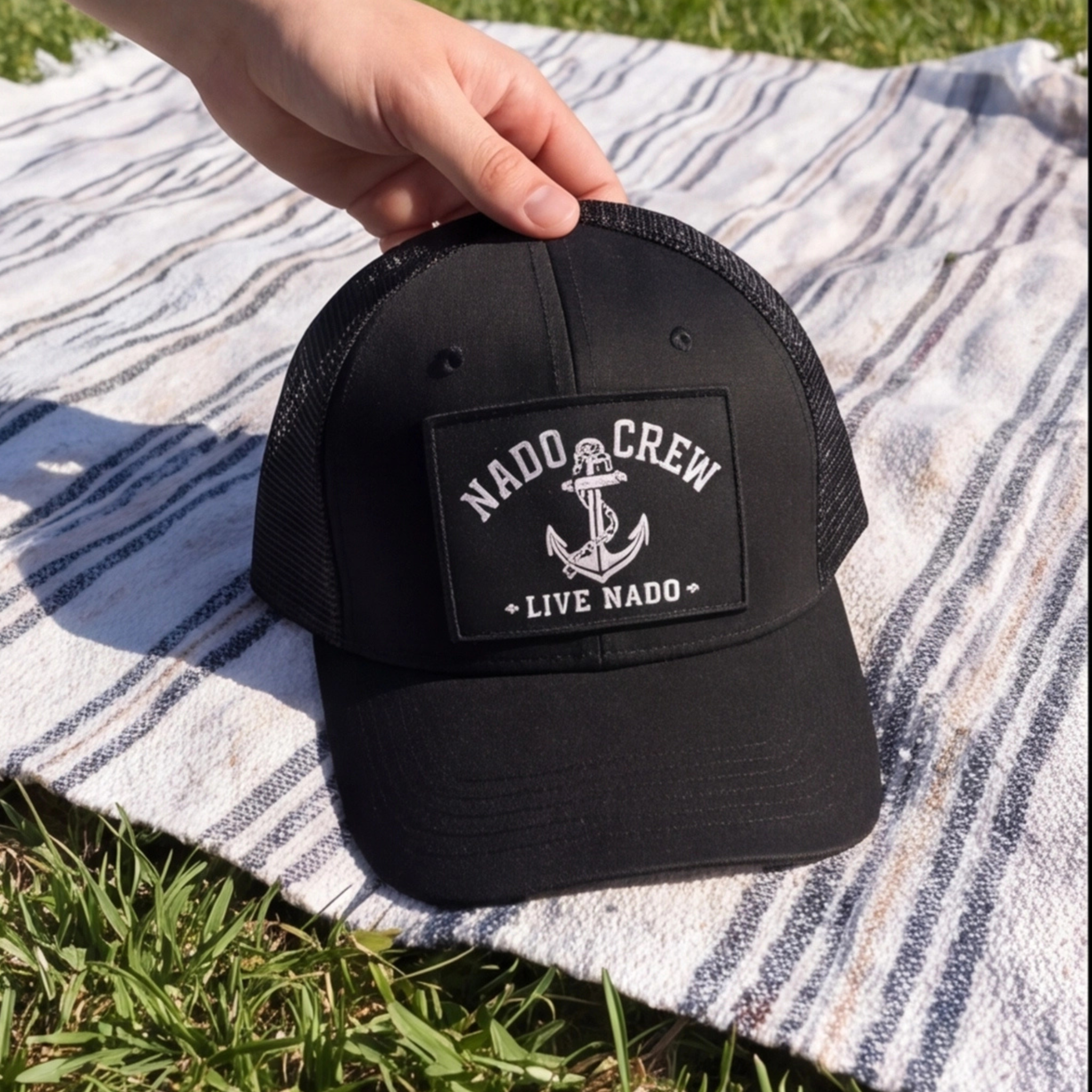 Black cap with 'Nado Crew' logo on a striped fabric background