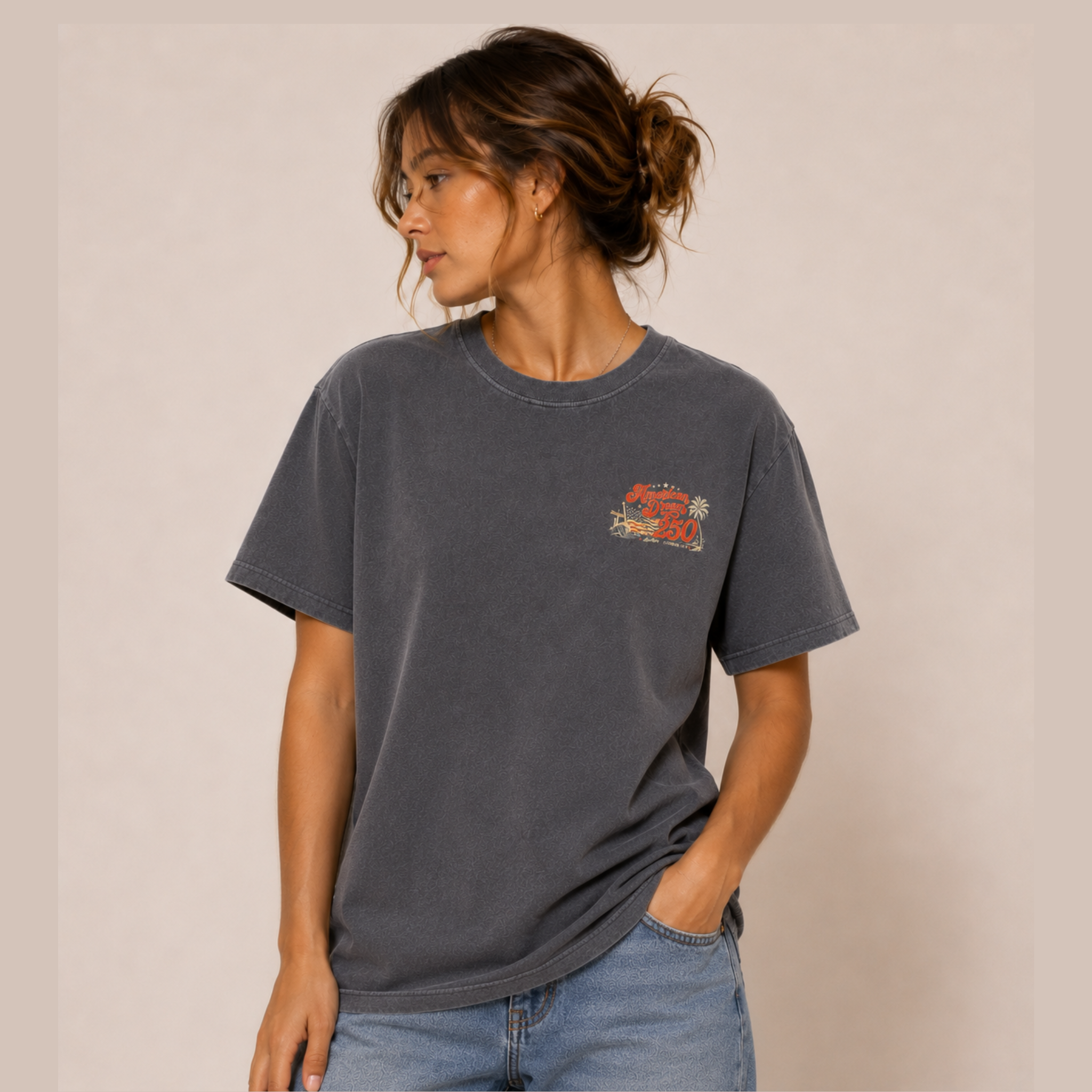 Woman wearing a dark gray t-shirt with a small graphic on a beige background