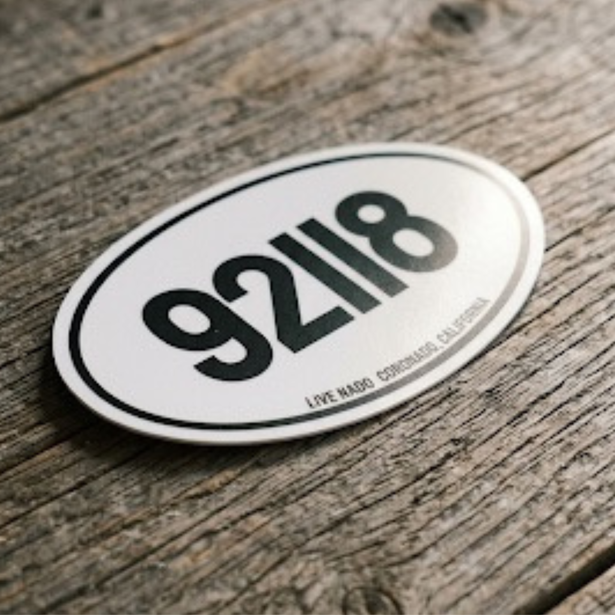 Oval-shaped sticker with '92118' on a wooden surface