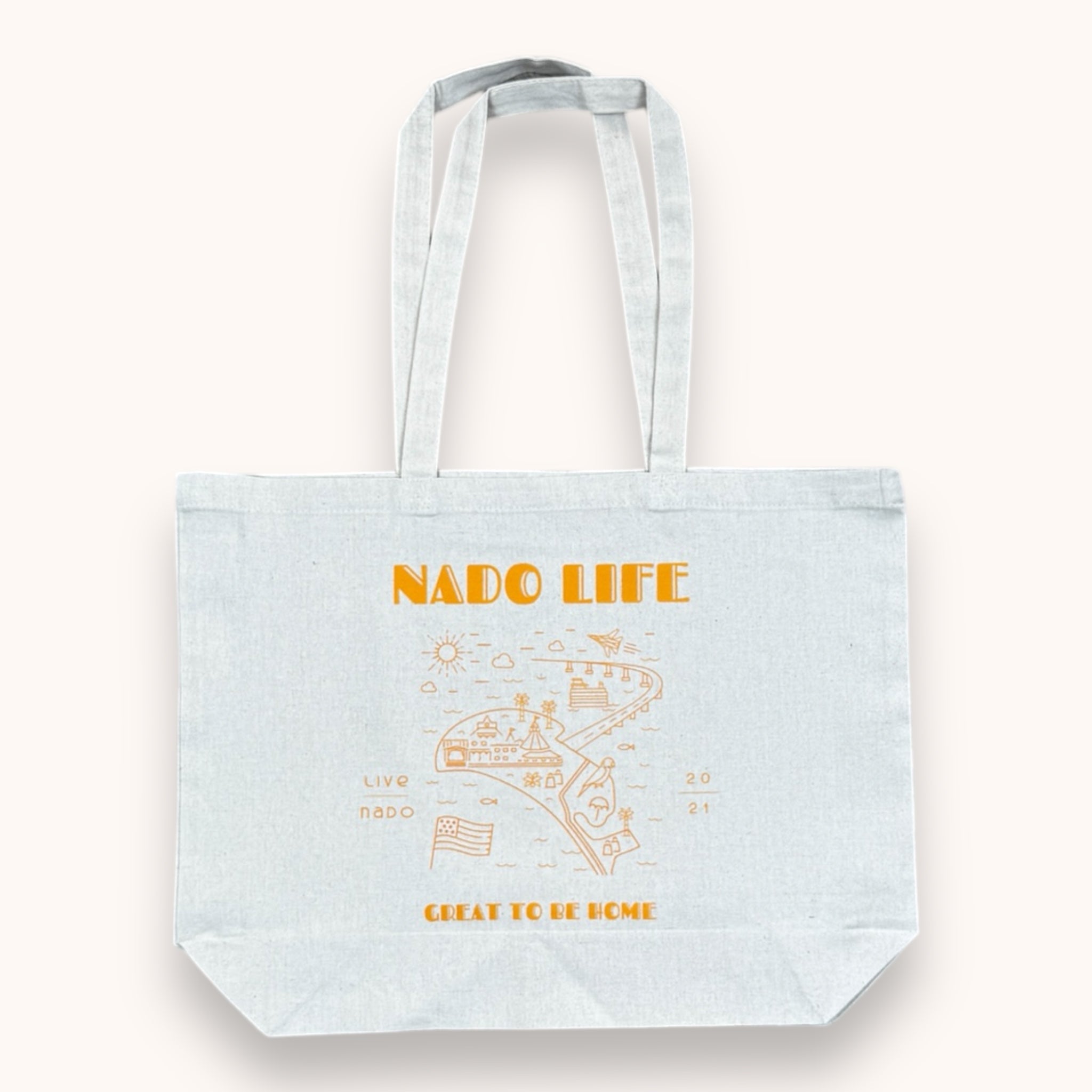 A white cotton tote bag with 'NADO LIFE' and 'GREAT TO BE HOME' printed in orange, along with playful icons such as a parrot, ferry boat, and American flag.