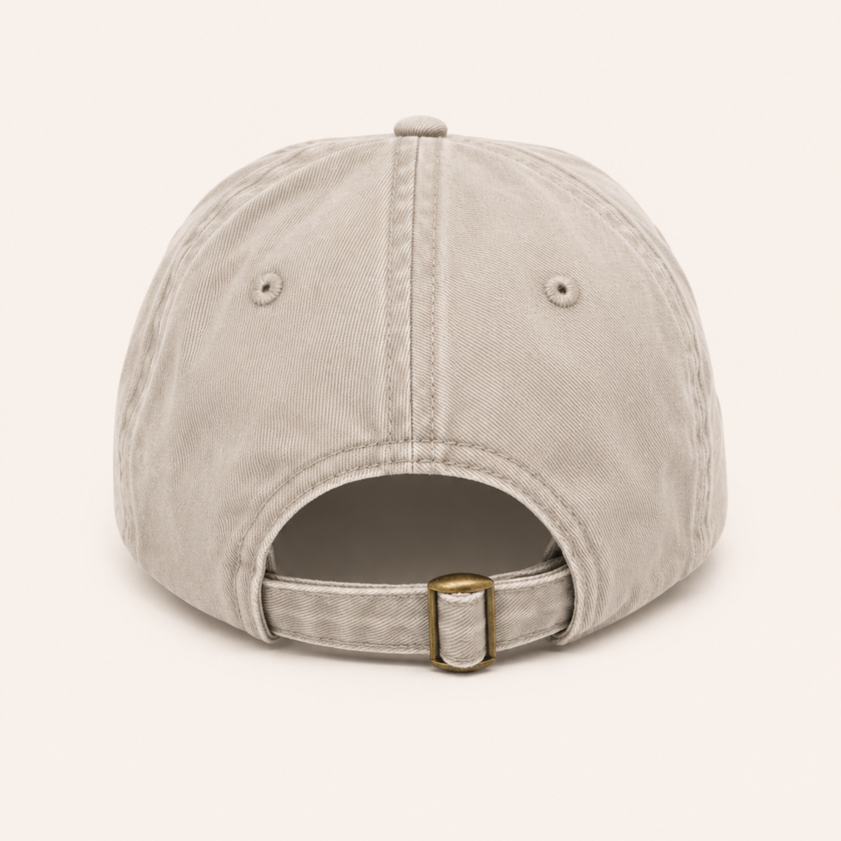 Back view of a tan cotton baseball cap with an adjustable fabric strap and brass buckle closure.