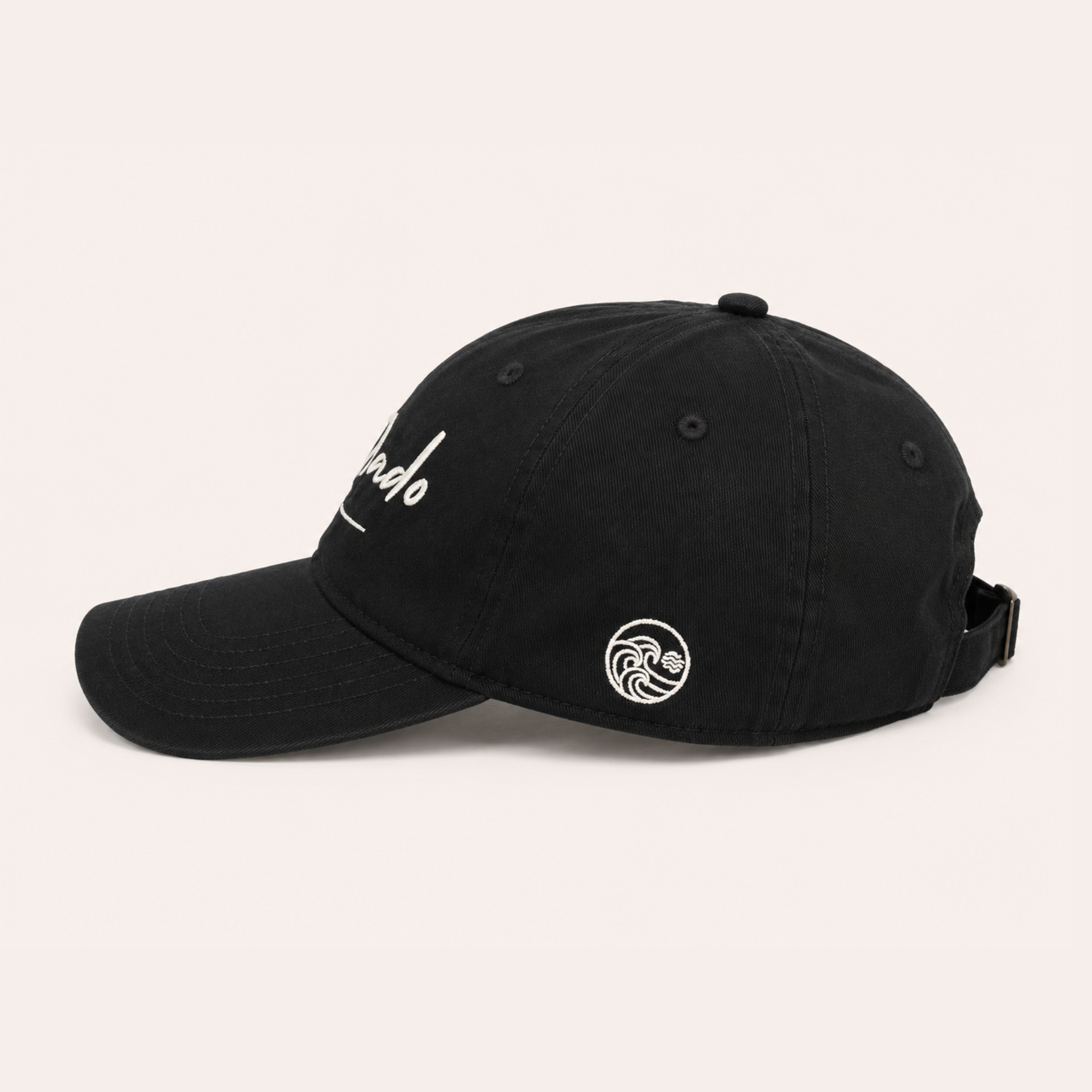 Side view of a black baseball cap featuring a small white embroidered wave logo on the side panel.
