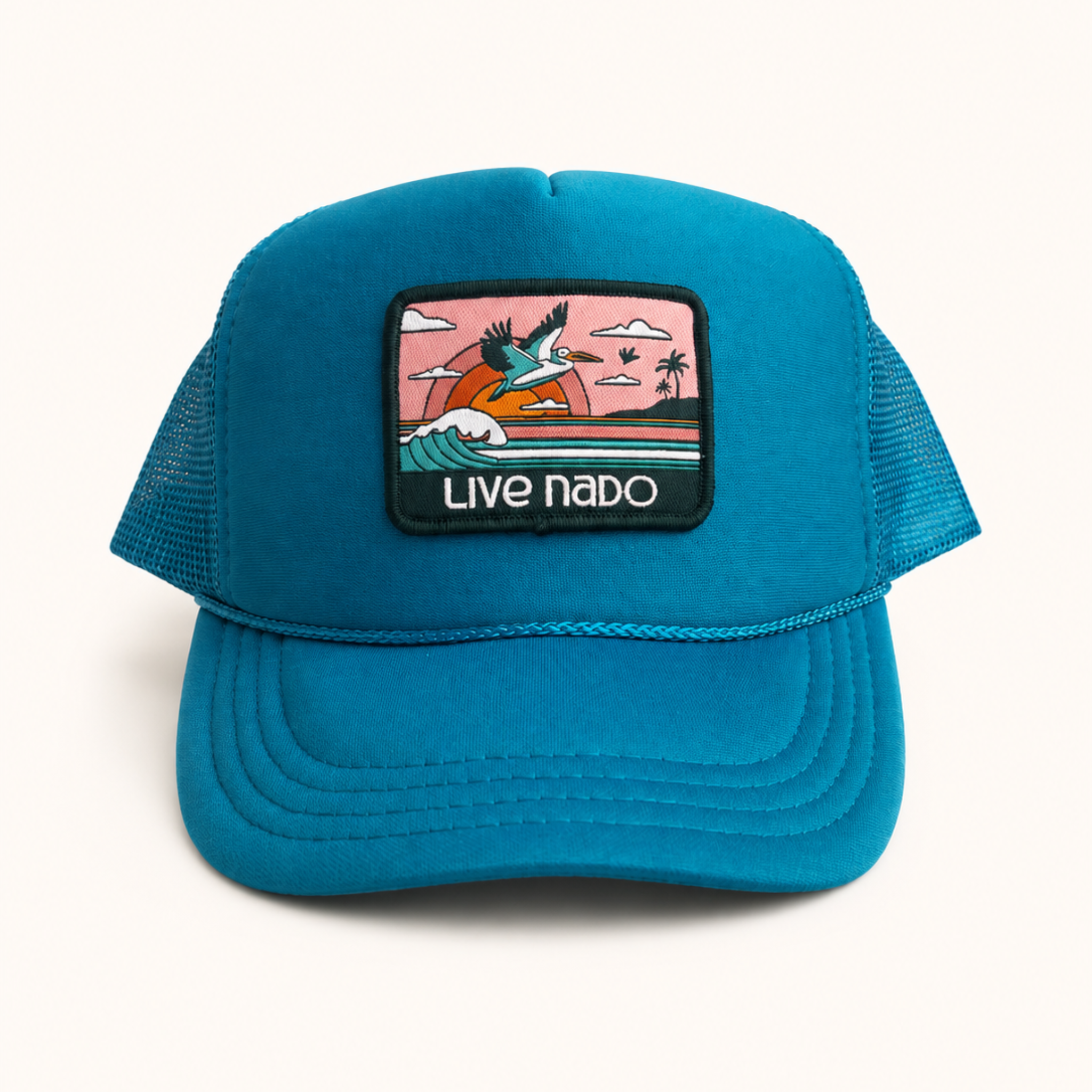 Blue cap with a colorful patch featuring a beach scene and 'Live Nado' text on a white background.