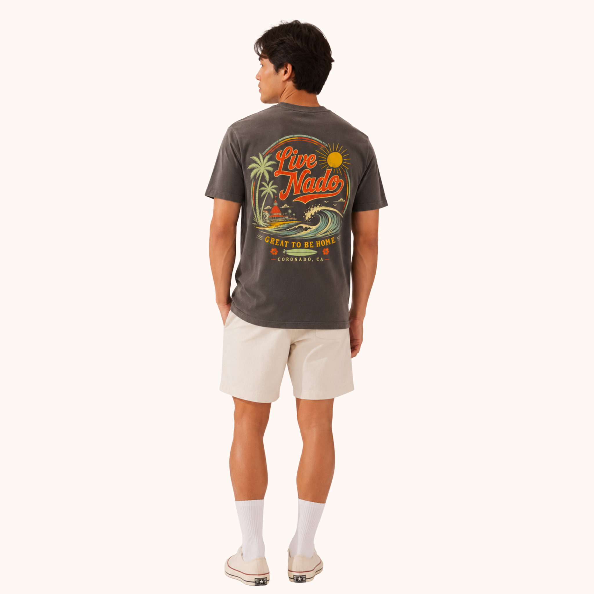 Back view of a man wearing a charcoal gray t-shirt featuring a large graphic with "Live Nado," palm trees, a surfboard, and a beach scene.